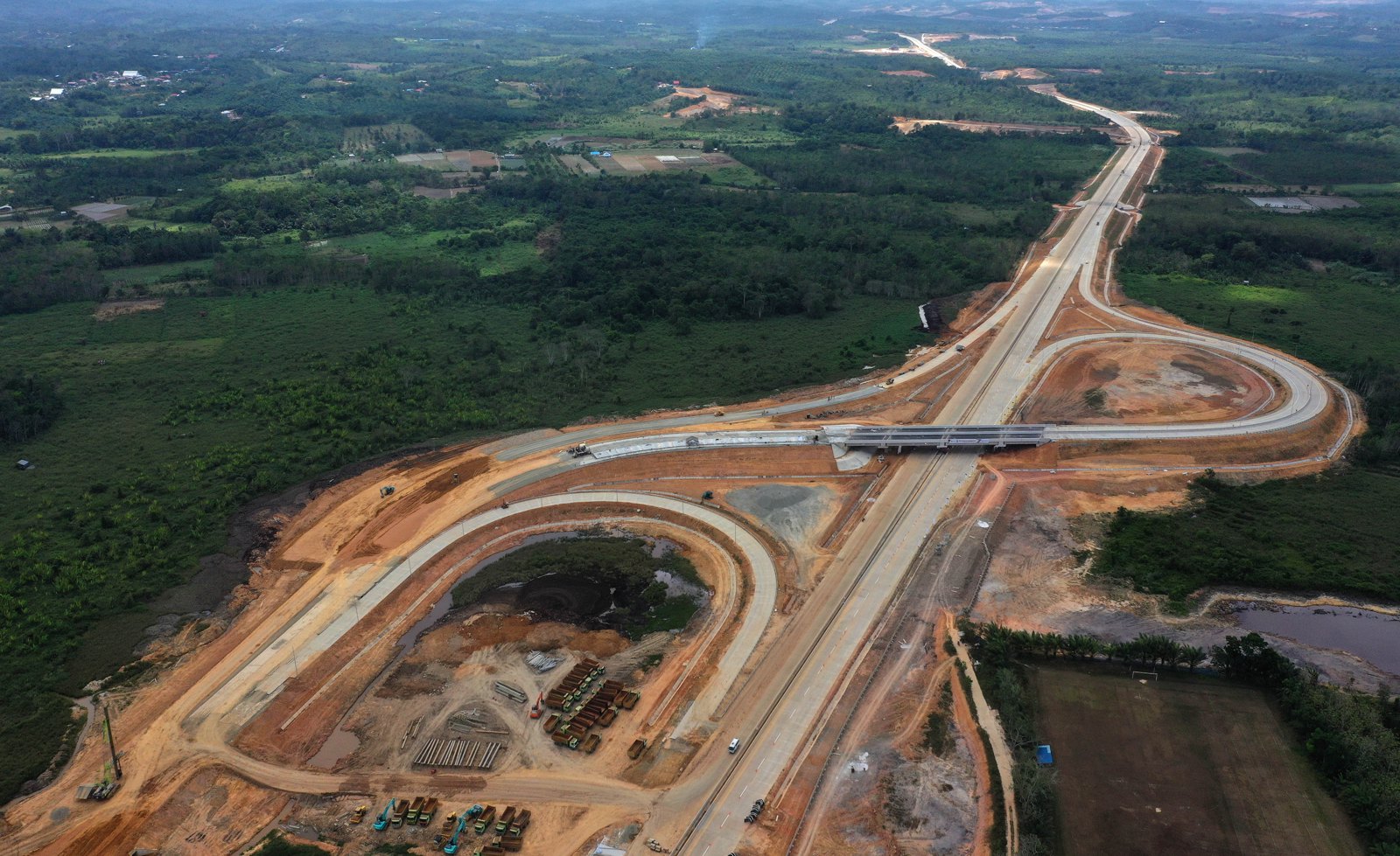 Aerial view of an active roadway construction site with graded earth and erosion controls